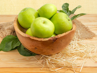 Green apples with leaves in the vintage wooden fruit bowl