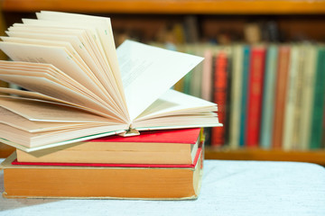 Open book, stack of hardback books on table. Top view.