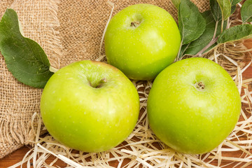 Green apples on wood wool and burlap close-up