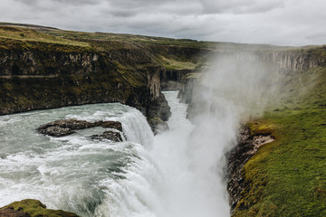 scenic view of steam above beautiful Gullfoss waterfall  flowing through highlands in Iceland