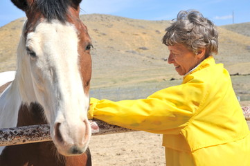 Mature female senior bonding with her horse on the ranch outdoors.