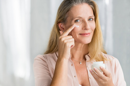Woman applying anti aging lotion on face