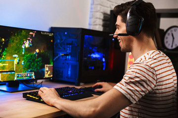 Portrait of professional gamer guy playing video games on computer, wearing headphones and using backlit colorful keyboard © Drobot Dean