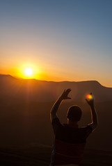 Man holding sunrays in montains