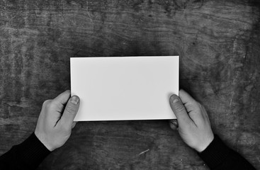monochrome photo male hands holding a white blank sheet of paper