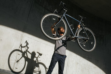 Mann hebt voller Freude sein Fahrrad in die Luft