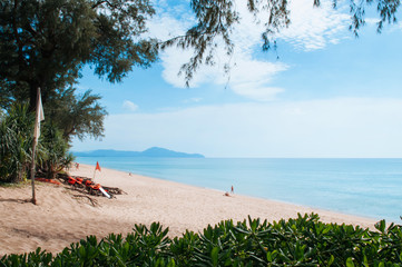 Trop[ical Phuket vibrant turqoise blue sea at Mai Khao beach with tourists