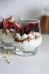 Fresh figs with vanilla whipped cream, cheese, nuts and maple syrup in a glass beaker. Healthy beverage. Healthy food, dieting and breakfast concept. Freshly made yoghurt with seeds and fruits