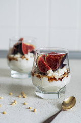 Fresh figs with vanilla whipped cream, cheese, nuts and maple syrup in a glass beaker. Healthy beverage. Healthy food, dieting and breakfast concept. Freshly made yoghurt with seeds and fruits