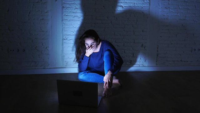 Sad and scared female Young woman with computer laptop suffering cyberbullying and harassment being online abused by stalker or gossip feeling desperate and humiliated in cyber bullying concept.