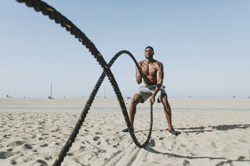 Fit man working out with battle ropes