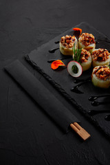 close-up view of delicious sushi roll with creamy eel and kimchi mayonnaise on slate board and chopsticks