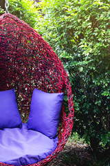 hanging wicker chair with pillow among the leaves and trees peace rest joy color