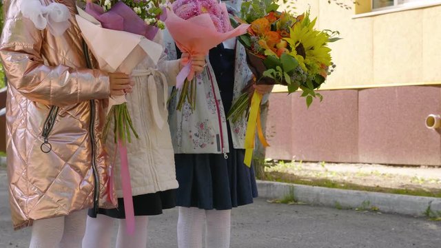 Adorable female schoolchildren with flowers, crane shot