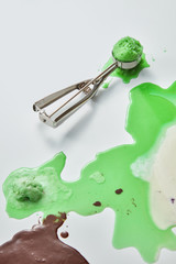 Brown, green and white splashes of ice cream with a scoop of homemade ice cream on a gray background with copy space. Top view
