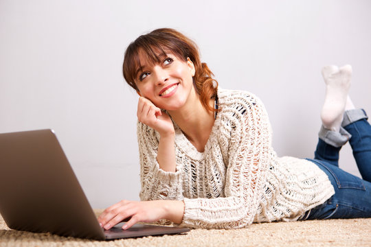 happy young woman lying on floor with laptop computer