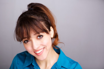 Close up smiling young woman against gray wall