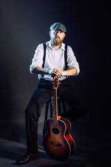 Fototapeta premium A bearded man in hat with guitar in studio