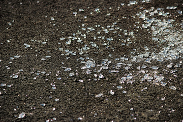 transparent shards of a windshield from the car on asphalt of parking.