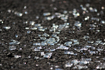 transparent shards of a windshield from the car on asphalt of parking.