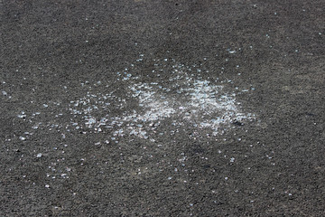 transparent shards of a windshield from the car on asphalt of parking.