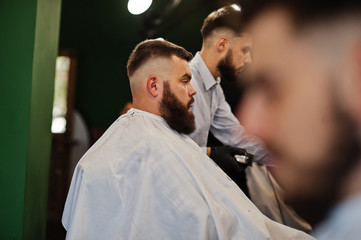 Handsome bearded man at the barbershop, barber at work.