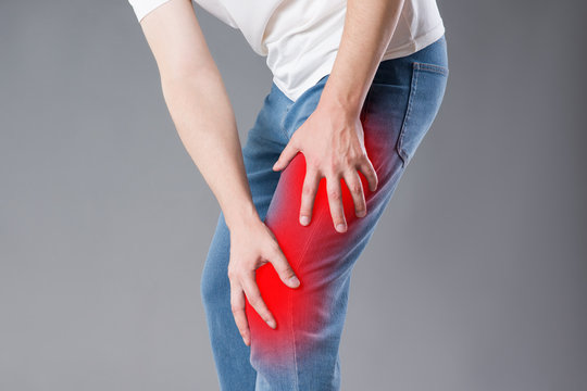 Man with pain in knee, studio shot on gray background