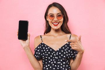 Woman isolated over pink background showing display of mobile phone.