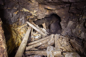 Underground abandoned gold iron ore mine shaft tunnel gallery passage with timbering wooden