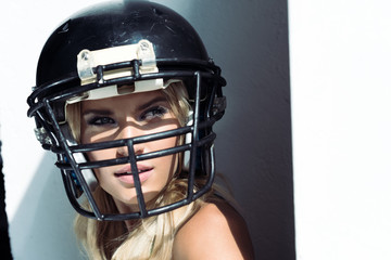 close-up portrait of young woman in sport bra and american football helmet on white