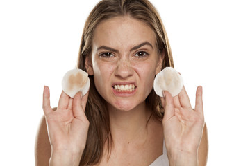 young disgusted girl showing a dirty cotton pads on white backgeound