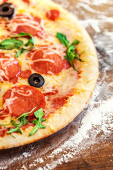 Hot pizza with Pepperoni, arugula and cheese on a rustic wooden table closeup. Pizza Ready to Eat. Top view.