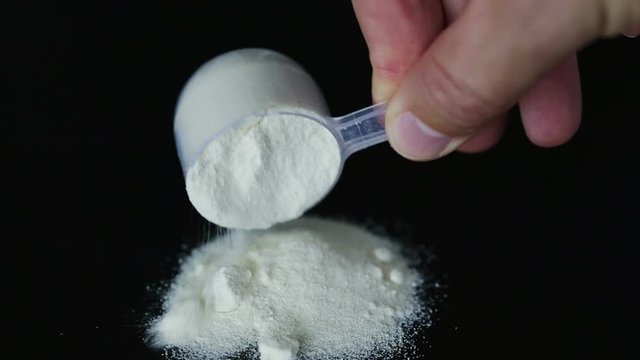 A man pours a measuring glass of a portion of protein, amino acids, glutamine bcaa.