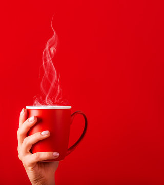 Woman with a cup of fragrant coffee in her hands on a cool day. Black warm coffee in cold weather.Coffee on a red background for your design. Advertising coffee.