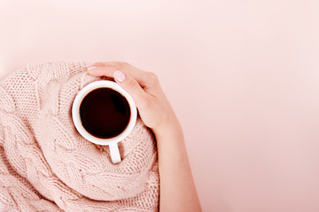 Woman with a cup of fragrant coffee in her hands on a cool day. Black warm coffee in cold weather. View from above.