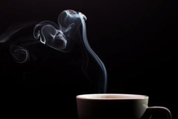 A cup of fragrant coffee on a black background for your design. Advertising coffee. Aroma steam in the shape of a heart.