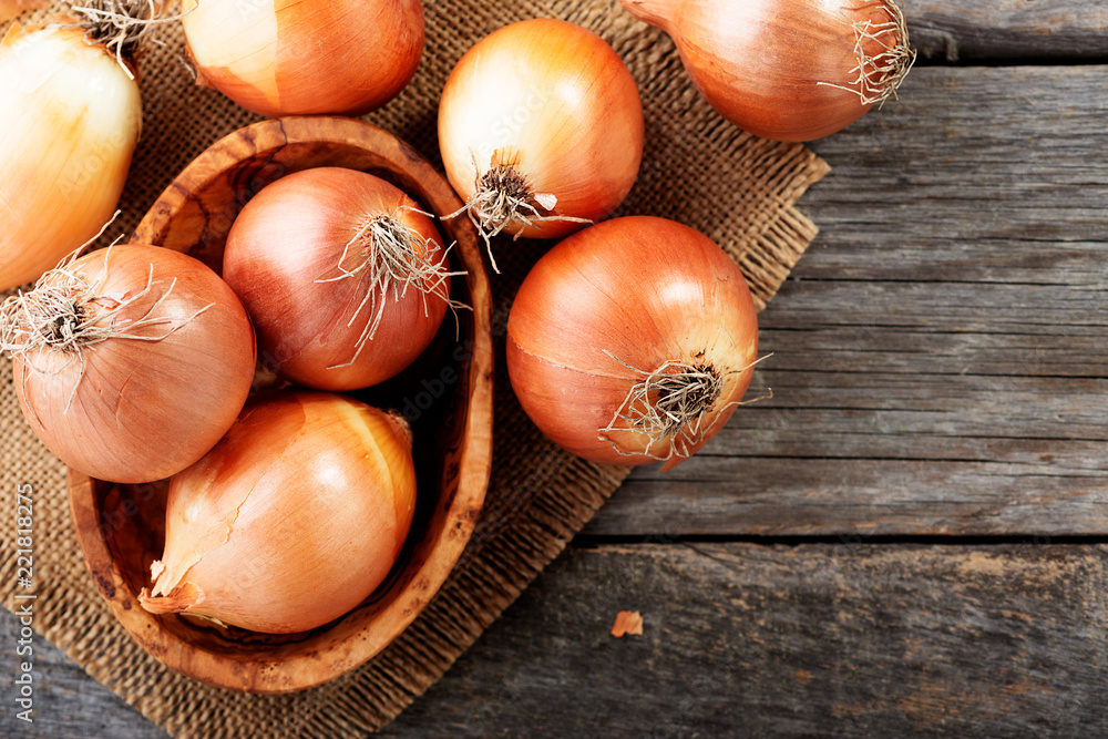 Wall mural fresh raw onions on wooden background. top view.