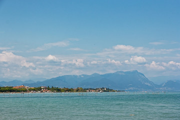 Fototapeta premium Italy - Lake Garda. Blue waters are lush greenery of Italian nature and the mighty slopes of the Alpine mountains.