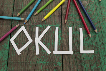 write Okul with colorful pens on the green wooden background for education and back to school concept. 