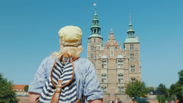 A tourist with a backpack goes to the Rosenborg Palace in Copenhagen. Visit Denmark and tourism in Scandinavia