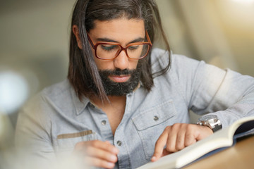 Dark-haired man with eyeglasses reading book