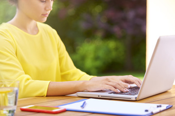 Cropped shot of a woman's hand typing on laptop