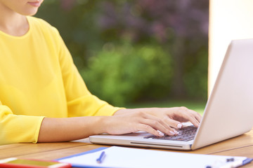Cropped shot of a woman's hand typing on laptop