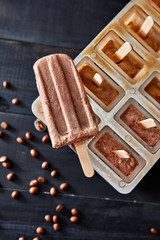 ice cube container with coffee espresso and milk popsicles, with coffee beans on dark wooden background, flat lay