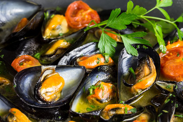 Delicious mussels from Taranto, with tomatoes and parsley, close-up - obrazy, fototapety, plakaty