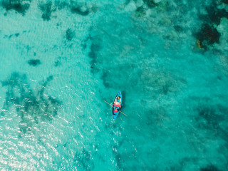 Top view of turquoise ocean water and fisherman on boat, aerial drone shot
