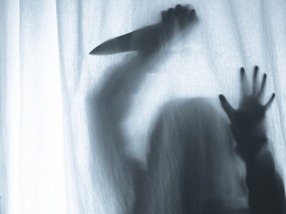 Screaming human pressing through fabric curtain as horror background . Trapped in shadows