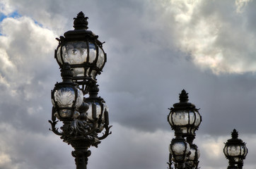 Fototapeta na wymiar Lanterns on the Pont Alexandre III against a cloudy sky in Paris 
