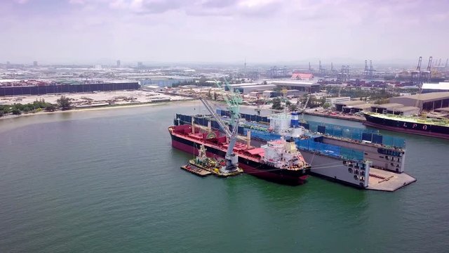 Aerial view of logistics concept a cargo ship being retrofit, repair and services on a floating dry dock off the coast at Laem Chabang dockyard in Chonburi Province, Thailand