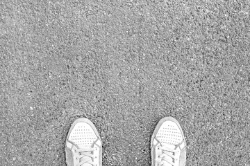 Legs sneakers on pavement, the arrow shows the direction